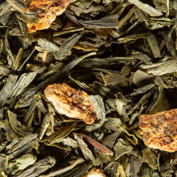 Gros plan sur des feuilles de thé vert séchées parsemées de morceaux d'écorces d'agrumes et de tiges de menthe, évoquant le thé des Divas