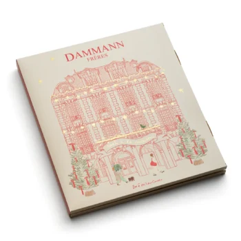 Calendrier de l'Avent Dammann Frères avec une illustration de façade haussmannienne, décoré de sapins et d'étoiles dorées pour Noël à la maison.