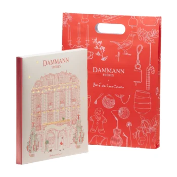 Calendrier de l'Avent Dammann Frères avec son sac cadeau rouge illustré par Zoé de Las Cases représentant un immeuble haussmannien festif