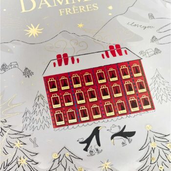 Illustration d'un calendrier de l'Avent Dammann Frères 2025, représentant une maison rouge enneigée avec 24 fenêtres, entourée d'arbres et de pingouins sur des patins à glace.