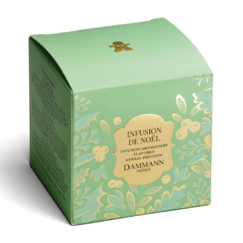 Boîte verte de tisane de Noël Dammann Frères ornée de motifs dorés, avec un petit dessin de bonhomme en pain d'épices sur le dessus