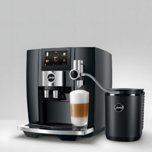 Vue d'ensemble de la machine à café JURA avec le refroidisseur de lait Cool Control 1L (EB) Black, montrant une tasse de latte macchiato fraîche et un design noir mat élégant.