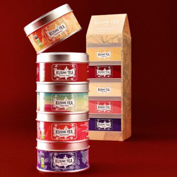 Coffret Kusmi Tea avec cinq boîtes métal empilées et une boîte ouverte en haut, présentant différentes infusions bio sans théine