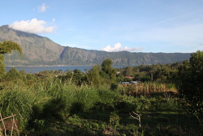 Vue panoramique d'une région agricole à Java, montrant un lac entouré de montagnes et une végétation luxuriante.
