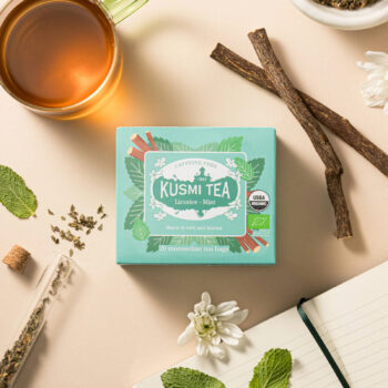 Boîte de Kusmi Tea réglisse menthe bio avec une tasse de thé, des bâtons de réglisse et des feuilles de menthe