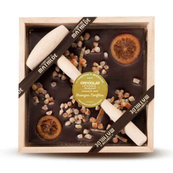 Tablette de chocolat noir 70% Le Comptoir de Mathilde avec oranges confites et fruits secs dans un coffret en bois, deux maillets disposés dessus