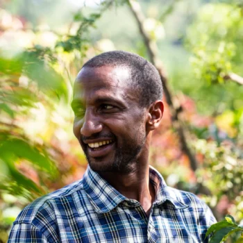 Producteur de café souriant portant une chemise à carreaux dans une plantation de café en Éthiopie