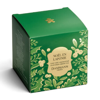 Boîte de thé vert aromatisé Dammann Frères Noël en Laponie, avec des motifs végétaux verts et dorés et un petit bonhomme en pain d'épices sur le dessus.