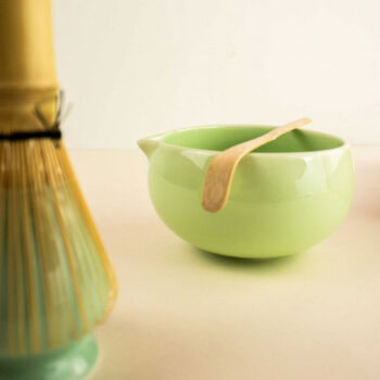 Chasen en bambou vert et bol à matcha vert clair avec une cuillère en bambou, ustensiles pour la préparation du thé matcha