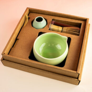 Coffret matcha Yoko Design présenté dans un emballage en carton, contenant un bol vert clair, un fouet Chasen en bambou, une cuillère Chashaku et un support pour fouet.