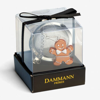 Boule à thé Dammann Frères en métal argenté avec pendentif bonhomme pain d'épices, dans sa boîte transparente.