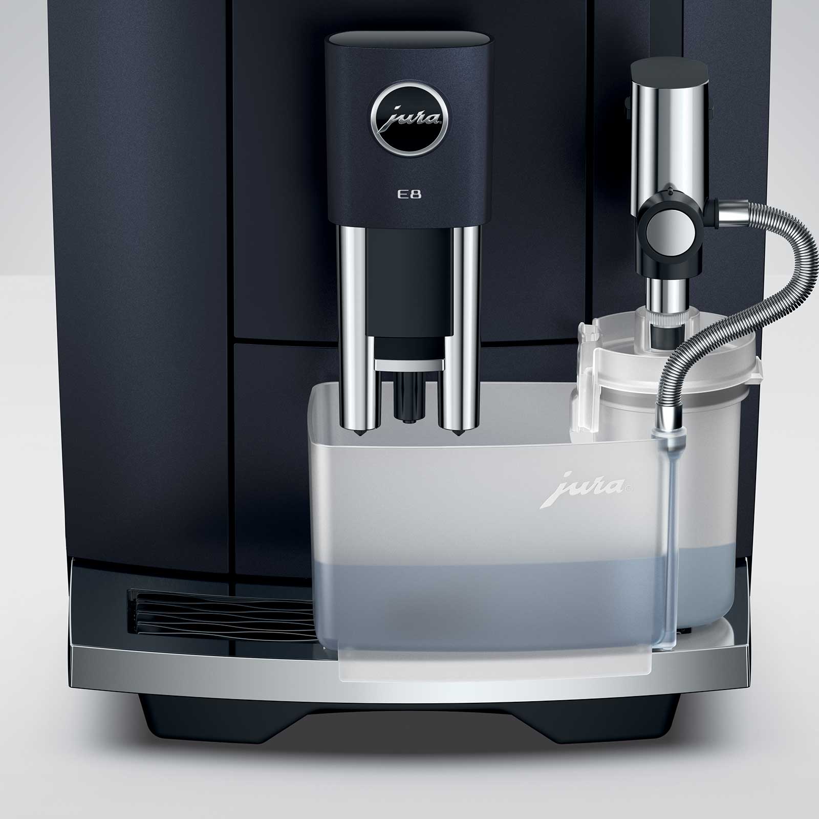 Gros plan sur la machine à café JURA E8 Cosmic Black, montrant le bec verseur chromé avec les deux becs, le réservoir d'eau transparent et la buse de lait chromée.