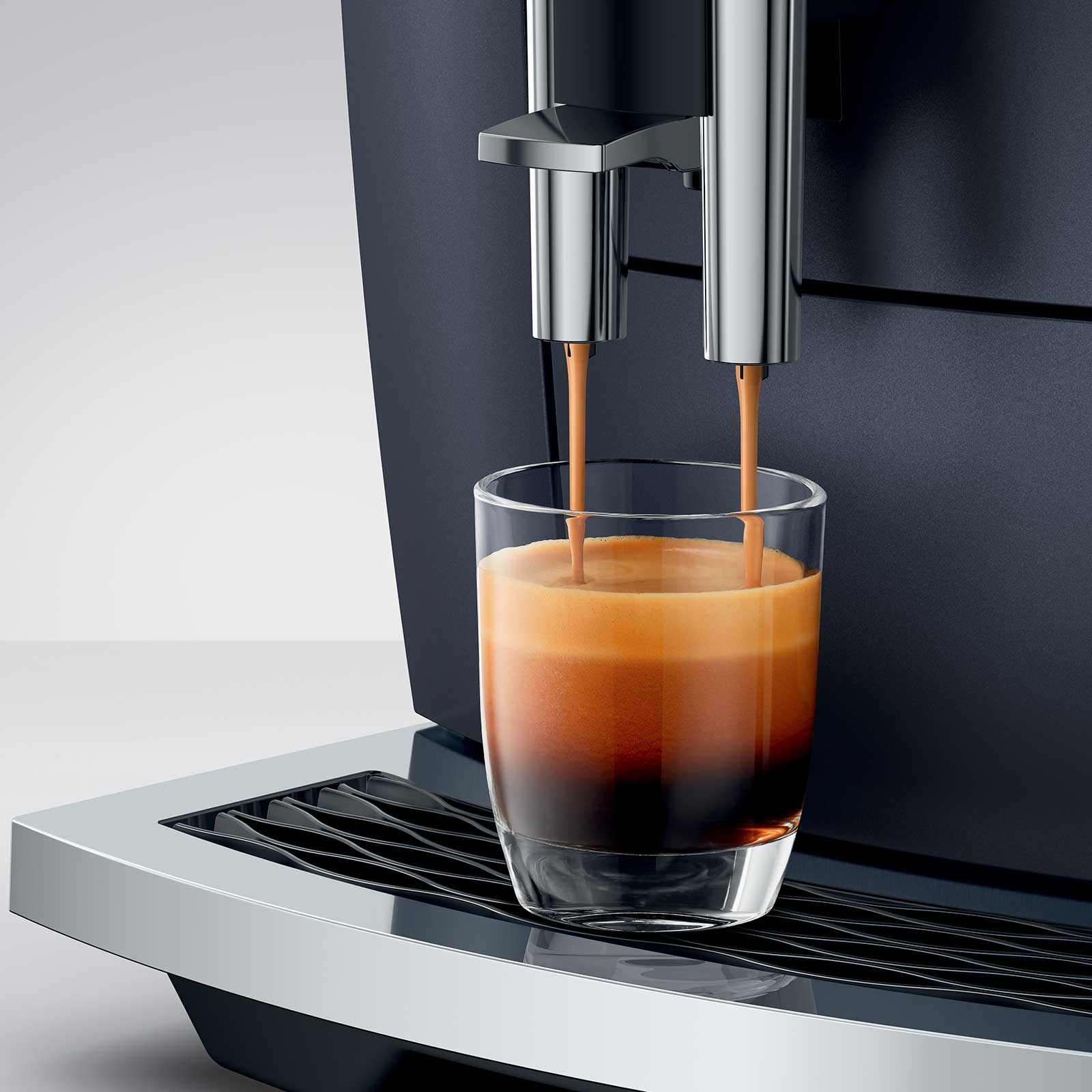 Machine à café JURA E8 Cosmic Black versant un espresso crémeux dans un verre transparent, avec une mousse dorée parfaite