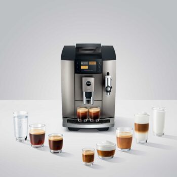 Machine à café automatique Jura E8 Midnight Silver entourée de plusieurs tasses de café préparées : expresso, cappuccino, latte macchiato et verre d'eau.