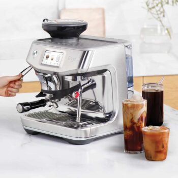 Machine à expresso Sage The Barista Touch Impress en acier inoxydable, avec trois verres de café glacé devant, dont un avec de la crème et de la glace.