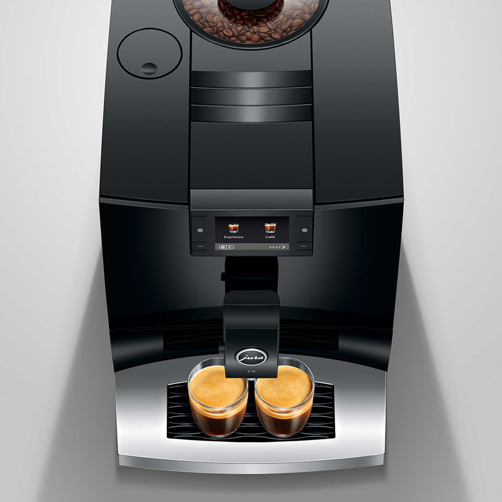 Machine à café JURA C9 Piano Black préparant deux espressos dans des tasses transparentes, avec affichage du logo Jura.