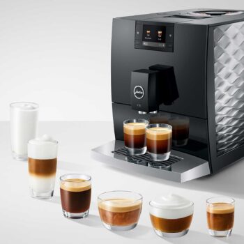 Machine à café automatique Jura C9 Piano Black avec 7 tasses de café préparées de différentes tailles et types, dont un cappuccino et un espresso.