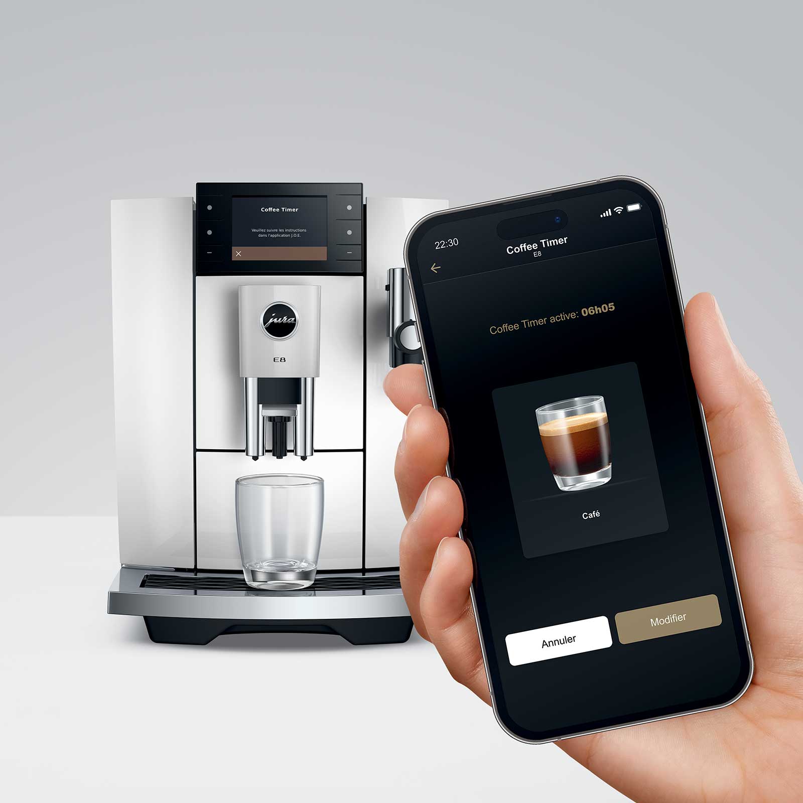 Machine à café JURA E8 Piano White avec un smartphone affichant l'application Coffee Timer, contrôlant la préparation du café.