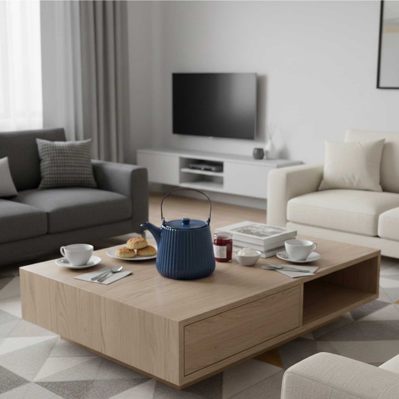 Théière Bastide Tiao bleu foncé en grès émaillé, posée sur une table basse en bois, accompagnée de tasses et de scones