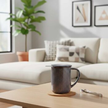 Tisanière Bastide Tiao gris noir avec couvercle et infuseur en inox, posée sur un dessous de verre en liège sur une table en bois