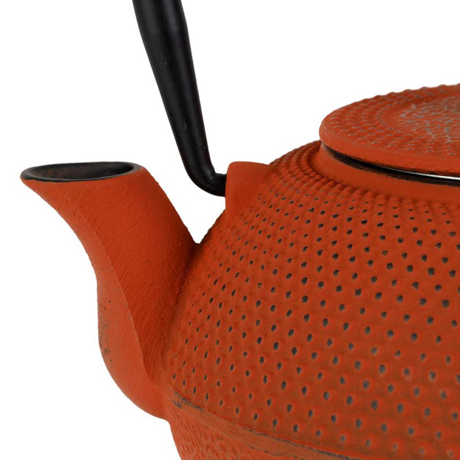 Gros plan sur une théière en fonte de couleur terracotta avec des picots, bec verseur et anse noire visible