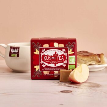 Boîte de Kusmi Tea Vanille-Pomme-Caramel façon Tatin avec une tasse, une part de tarte et des morceaux de pomme