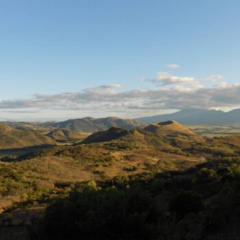 Paysage vallonné et verdoyant de Chalatenango, Salvador, sous un ciel bleu parsemé de nuages, évoquant un terroir de café
