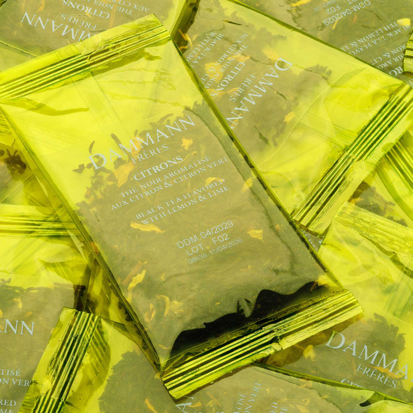 Plusieurs sachets de thé glacé Dammann Frères Citrons, emballages jaunes brillants avec des feuilles de thé visibles