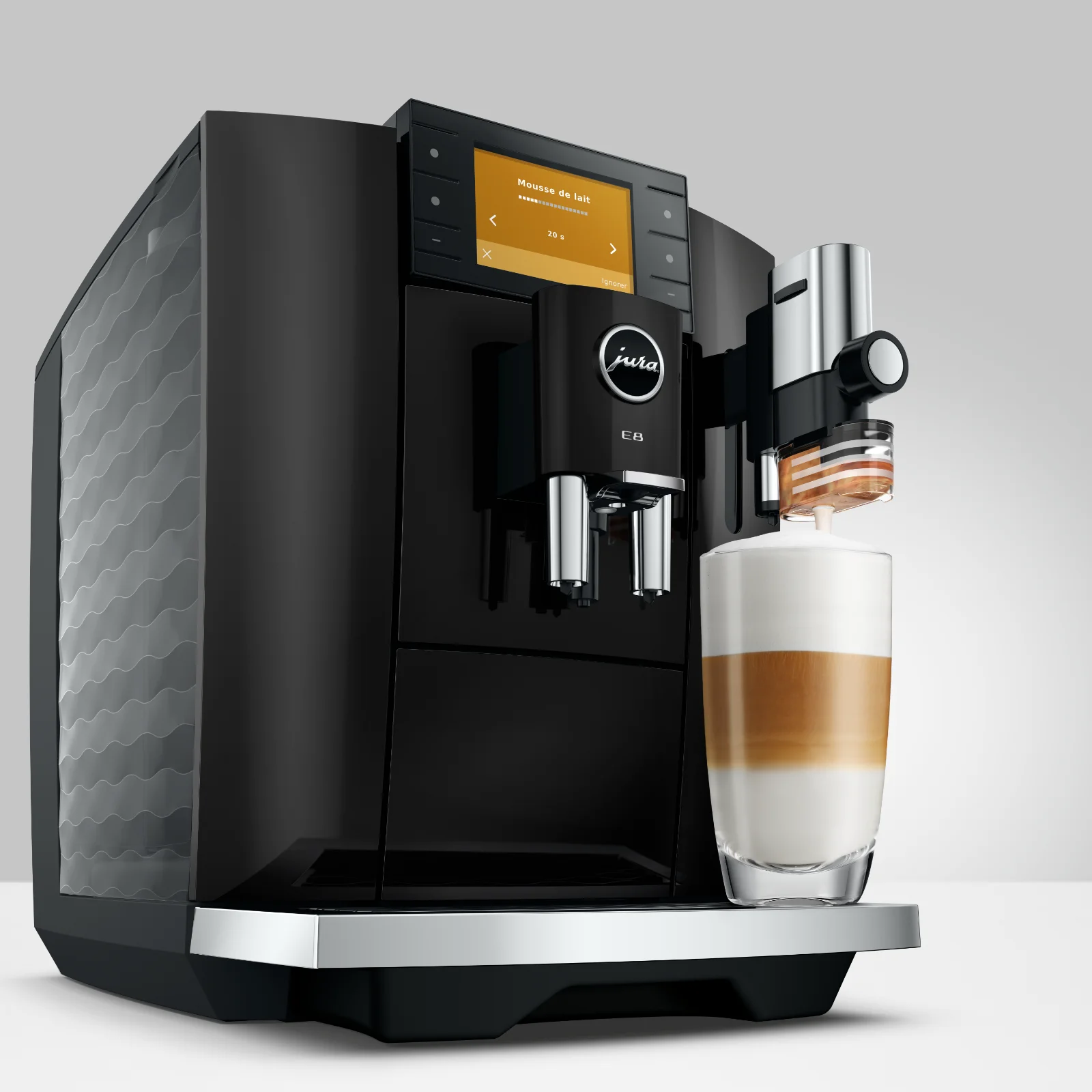 Machine à café automatique Jura E8 Piano Black préparant un latte macchiato dans un verre transparent, avec écran tactile affichant 'Mousse de lait'
