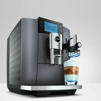 Machine à café automatique Jura E10 noire avec écran tactile, préparant une boisson lactée colorée dans un verre design sur le repose-tasse