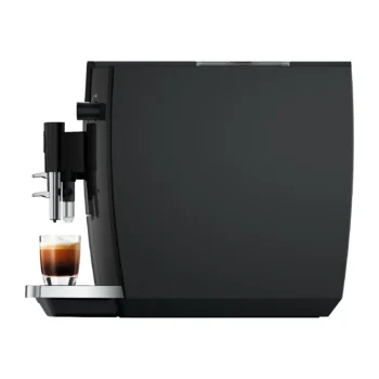 Machine à expresso automatique noire vue de profil, préparant un café dans une tasse en verre transparent sur le repose-tasse métallique