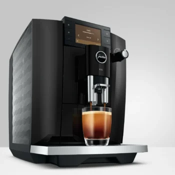 Machine expresso automatique Jura E6 noire préparant un café dans un verre transparent sur fond gris