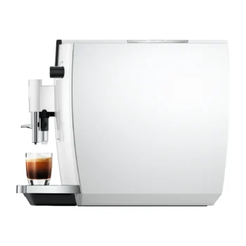 Machine à expresso automatique Jura blanche de profil distribuant un café dans une tasse en verre sur le plateau repose-tasses