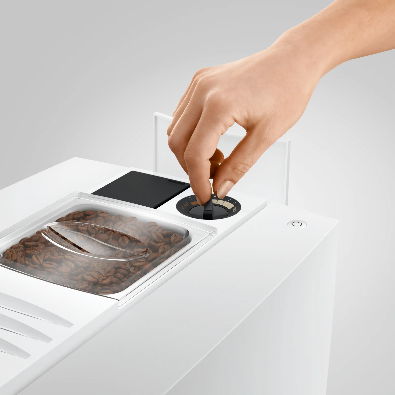 Main réglant la finesse de mouture sur le sélecteur d'une machine à café automatique avec réservoir de grains visible
