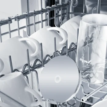 Tasses blanches et verre transparent Jura rangés sur la clayette supérieure d'un lave-vaisselle, illustrant l'entretien des accessoires