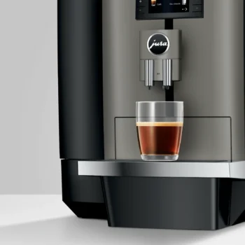 Cafetière automatique Jura X4 avec un verre rempli de café noir sur le repose-tasse en métal, design élégant pour expresso