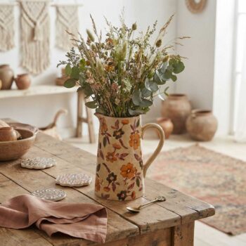 Pichet en céramique à motif floral automnal rempli d'un bouquet de fleurs séchées sur une table en bois rustique