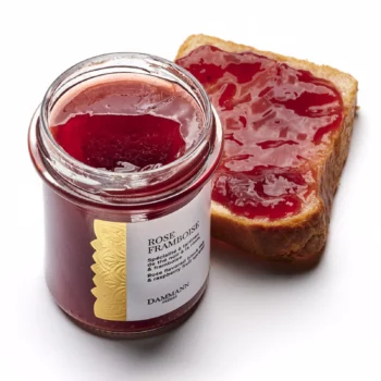 Pot de confiture Rose Framboise de Dammann Frères à côté d'une tranche de pain nappée de cette spécialité au thé noir et à la framboise