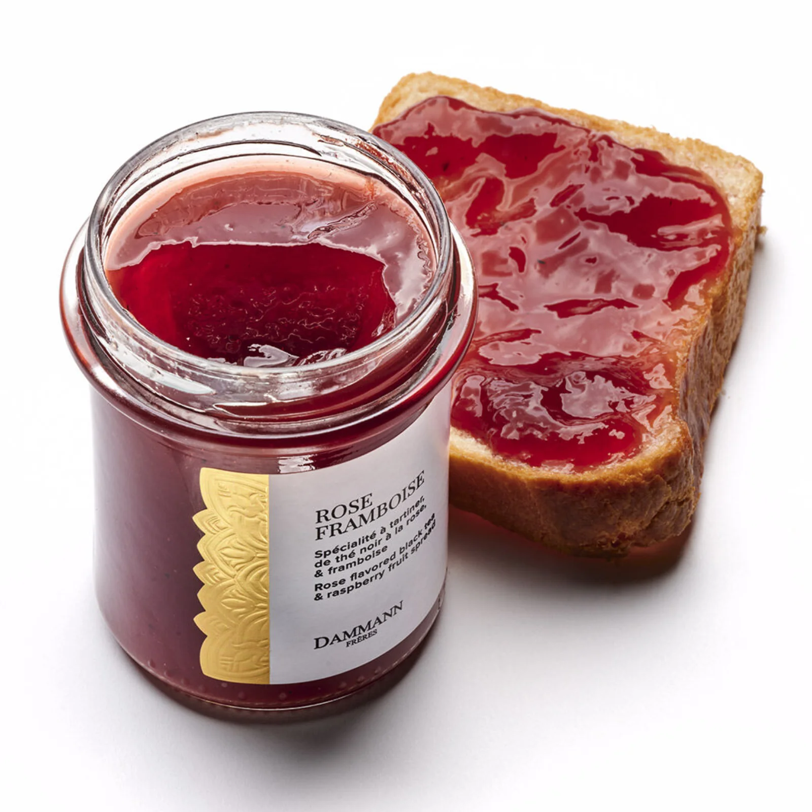 Pot de confiture Rose Framboise de Dammann Frères à côté d'une tranche de pain nappée de cette spécialité au thé noir et à la framboise