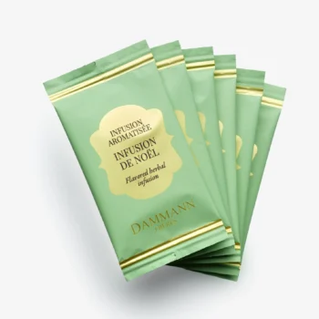 Sachets individuels d'infusion de Noël Dammann Frères disposés en éventail sur fond blanc, emballage vert clair avec détails dorés