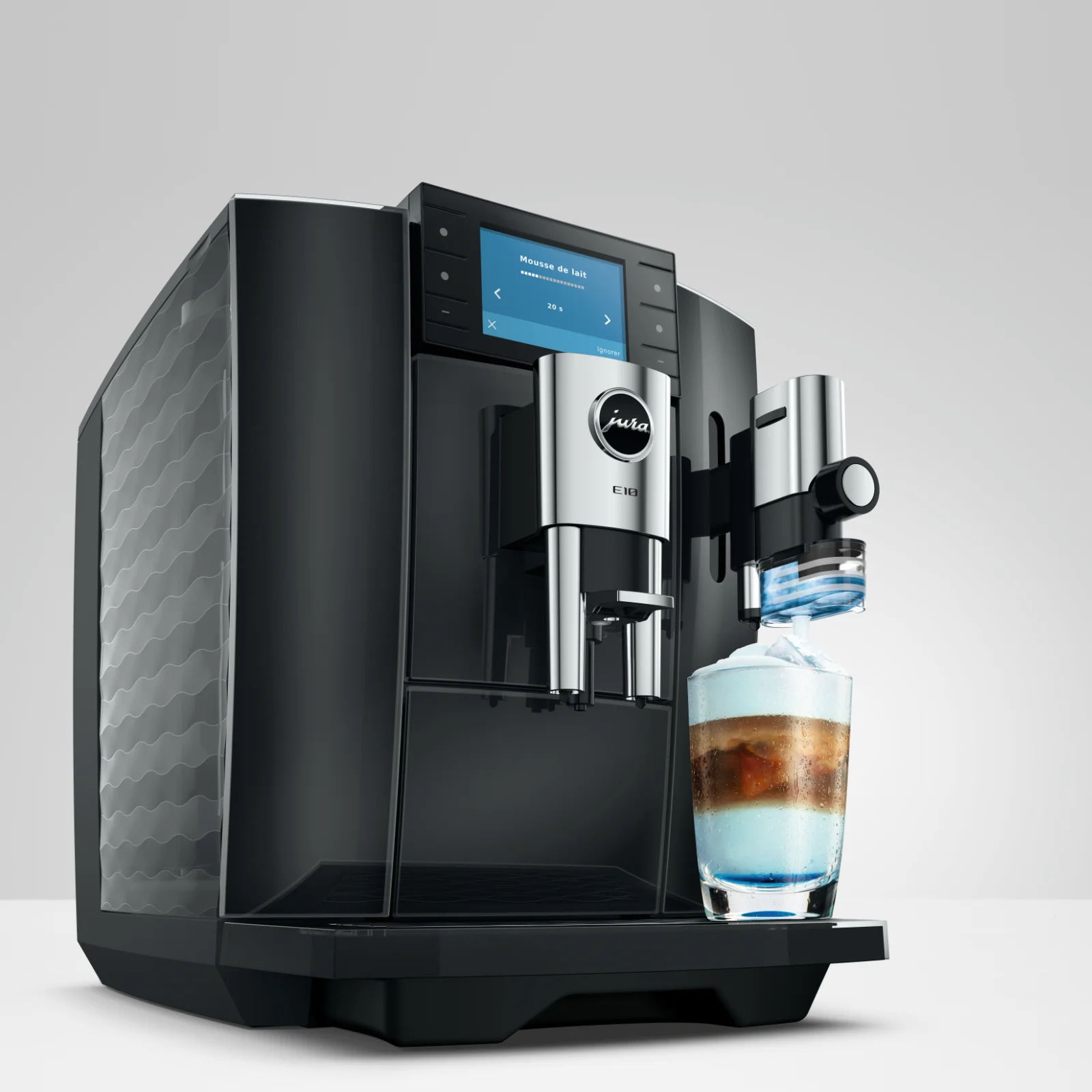 Machine à expresso automatique Jura E10 noire préparant une boisson latte avec une couche de mousse de lait dans un verre transparent