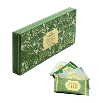 Boite verte décorée de motifs végétaux contenant un assortiment de thés et infusions de Noël Dammann Frères avec plusieurs sachets présentés devant