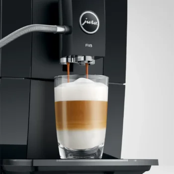 JURA A8 préparant un latte macchiato dans un verre, avec des couches de lait, de café et de mousse.