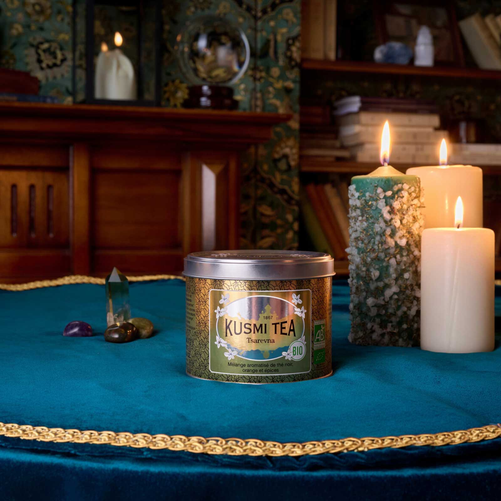 Boite de thé Tsarevna Kusmi Tea bio au milieu d'une table avec des bougies allumées et des cristaux, ambiance mystique et chaleureuse