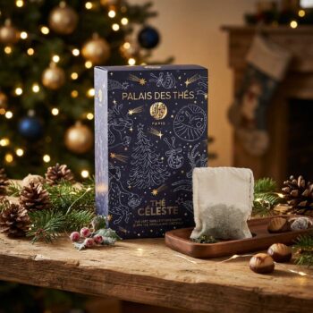 Boîte de Thé Céleste de Palais des Thés sur une table en bois avec un sachet de thé, entourée de décorations de Noël et sapin illuminé